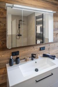 un lavandino da bagno con un grande specchio sopra di RiverVista Apartments by mi_vida a Bad Waltersdorf
