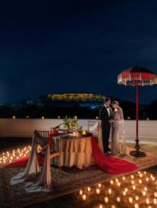 a bride and groom standing next to a table with an umbrella at Taj Usha Kiran Palace, Gwalior in Gwalior