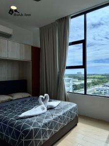 um quarto com uma cama com dois cisnes brancos em Hush Inn at ITCC Manhattan Suites em Kota Kinabalu