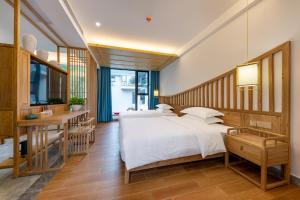 ein Schlafzimmer mit einem großen Bett und einem Schreibtisch in der Unterkunft Zhangjiajie Qiquan Vacation B&B in Zhangjiajie