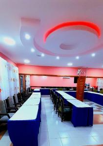 Quanam Woods Hotel في لودوار: غرفة بها طاولات وكراسي زرقاء وسقف احمر