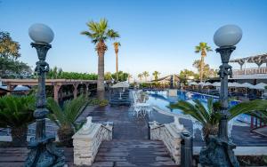 une piscine dans un complexe avec des palmiers et un pont dans l'établissement Golden Beach Resort & Spa, à Bodrum City