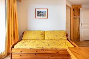 a bedroom with a bed with yellow sheets on it at Le Chartreuse - Apt de charme in Chamrousse