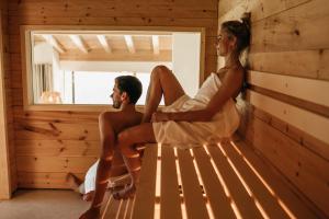 a man and woman sitting on a bench in a sauna at Der Jägersberg in Fischen