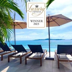 a group of chairs and an umbrella and the ocean at The Elysium Prațumnak Pattaya - By SHG in Pattaya South