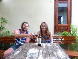 a man and woman sitting at a table with a glass of wine at villa Trúc Huy in Tân Thành (1)