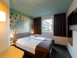 B&B Hotel Neuss في نويس: غرفه فندقيه بسرير ونافذه