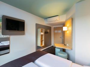 een kamer met een bed, een bureau en een televisie bij B&B Hotel Neuss in Neuss