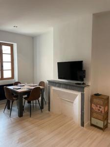 a living room with a table and a tv on a fireplace at Appartement entre la gare St Charles et Vieux port in Marseille