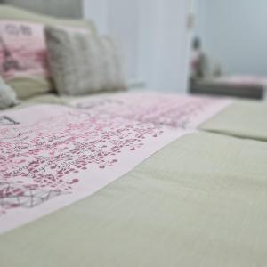 a close up of a bed with a pink pattern on it at APARTMAN MAYA 2 in Buzin