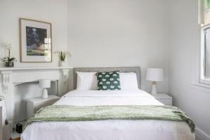 a bedroom with a white bed with a green blanket at Newtown Nest - Chic Terrace Living off King Street in Sydney