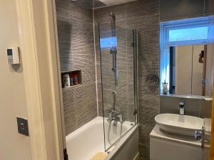 a bathroom with a shower and a tub and a sink at Ruislip Guest House in Ruislip