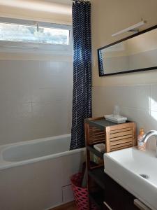 La salle de bains est pourvue d'un lavabo, d'une baignoire et d'un miroir. dans l'établissement Appartement Lumineux Vue Panoramique, à Ajaccio