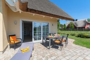 a patio with a table and chairs on a patio at Strandvilla "Babette" - BALO B, direkt am Meer, mit Sauna in Lobbe