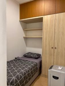 um pequeno quarto com uma cama e armários de madeira em Hush Inn at ITCC Manhattan Suites em Kota Kinabalu