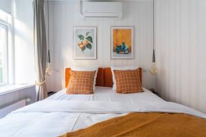 a bedroom with a bed with white sheets and orange pillows at Extravagant-2 bedrooms-Bronze in Copenhagen