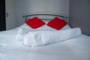a white bed with two red pillows on it at Chatham house in Etruria
