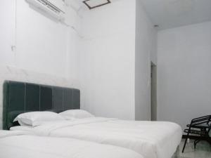 3 camas blancas en una habitación con cabecero verde en Hotel 889 Syariah Redpartner Banda Aceh, en Banda Aceh 2 fotos más