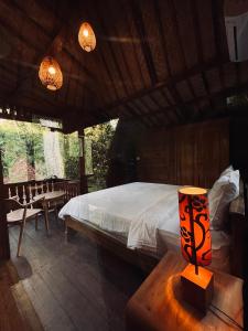 a bedroom with a bed and a table with a lamp at Bidja Room Wooden Joglo House in Sempidi