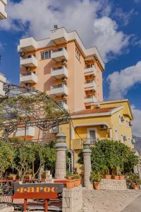 um edifício amarelo alto com árvores à frente em Hotel Pharos em Bar