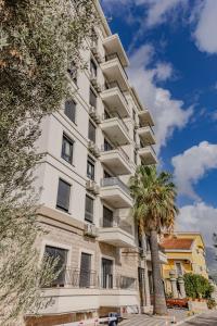 a white building with palm trees in front of it at Hotel Pharos in Bar