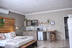 a bedroom with a bed and a table and a kitchen at De Akker Guest House Oudtshoorn in Oudtshoorn