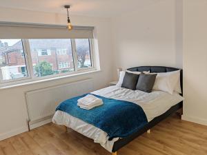 a bedroom with a bed with a blue blanket and a window at Charming 5 Bedroom House in Bexley in Bexley