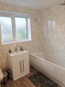 a bathroom with a white tub and a sink at Charming 5 Bedroom House in Bexley in Bexley