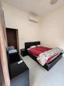 a bedroom with a bed with a red comforter at Couple room with attached bathroom in Dubai