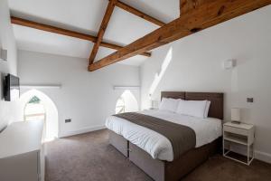 um quarto com uma cama grande, paredes brancas e tectos em madeira em The Old Chapel em Leyburn
