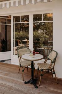 une table et deux chaises devant un restaurant dans l'établissement Chez Brens - Maison d'hôtes à La Hume, à Gujan-Mestras