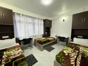 Habitación con 2 camas, sillas y ventana en Addy's Inn en Gangtok