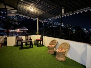 four chairs and a table on a balcony at night at Addy's Inn in Gangtok