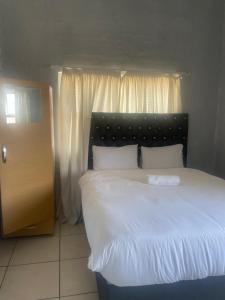 1 dormitorio con 1 cama grande con sábanas blancas en Stay Inn Lodge Boksburg, en Boksburg