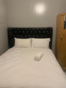 - un lit avec une tête de lit noire et des oreillers blancs dans l'établissement Stay Inn Lodge Boksburg, à Boksburg