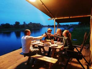 een groep mensen die rond een tafel op een dek zitten bij Camping de Boomgaard in Maaseik