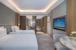 a hotel room with two beds and a flat screen tv at Shenzhenair International Hotel in Shenzhen