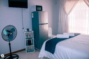 a bedroom with a refrigerator and a fan at BARAKA mtata ! in Mthatha