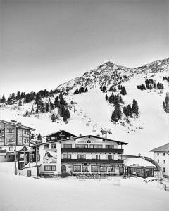 duży budynek przed pokrytą śniegiem górą w obiekcie Austria Alpinhotel Ski IN Ski OUT an der Edelweissbahn w mieście Obertauern