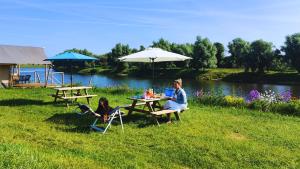 two people sitting at a picnic table with a laptop at Camping de Boomgaard in Maaseik