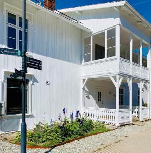 a white house with a balcony on a street at Apotekbygget in Nesbyen