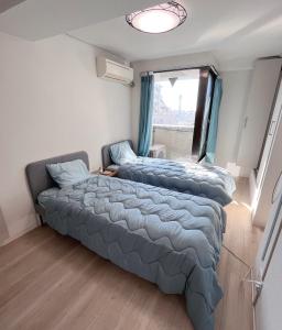 Duas camas num quarto com um sofá e uma janela em ホテルハヌル em Osaka