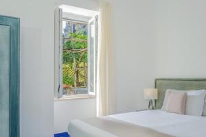 1 dormitorio con cama blanca y ventana en Residence Le Axidie en Vico Equense