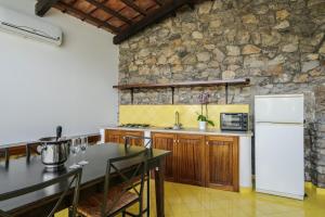 a kitchen with a table and a stone wall at Residence Le Axidie in Vico Equense