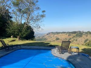 een zwembad met twee stoelen ernaast bij Churchill Cottage in Gillitts