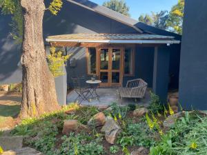 een blauw huis met een terras en een boom bij Churchill Cottage in Gillitts