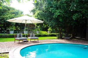 a swimming pool with two chairs and an umbrella at Paarl Hideaway in Paarl