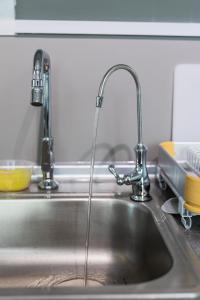 a kitchen sink with two faucets on it at HayBay Jesselton Quay Deluxe Seaview Suite 海景观 in Kota Kinabalu