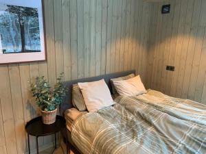 a bed in a room with a table and a potted plant at Skogly - Ny stor hytte, Unike Finnskogen in Torsby