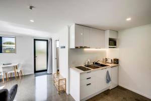 a kitchen with white cabinets and a table at Modern Studio near Clive River in Clive